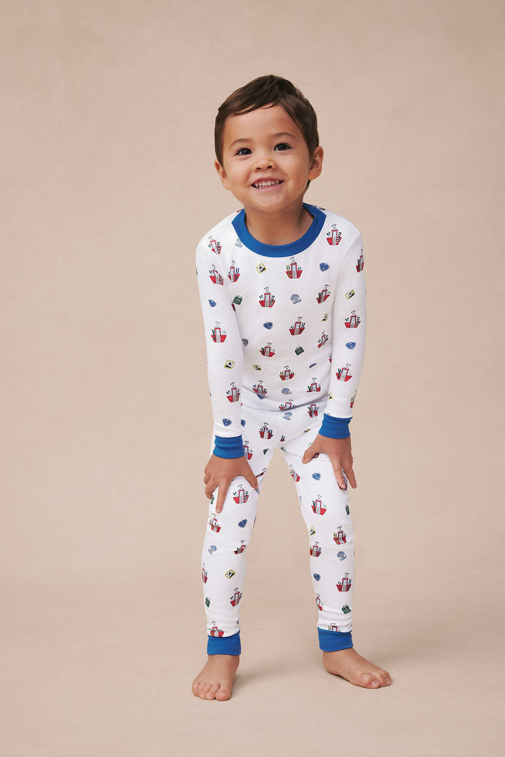 Child wearing white long-sleeve pajama top and matching pants with ski lift print and blue trim.