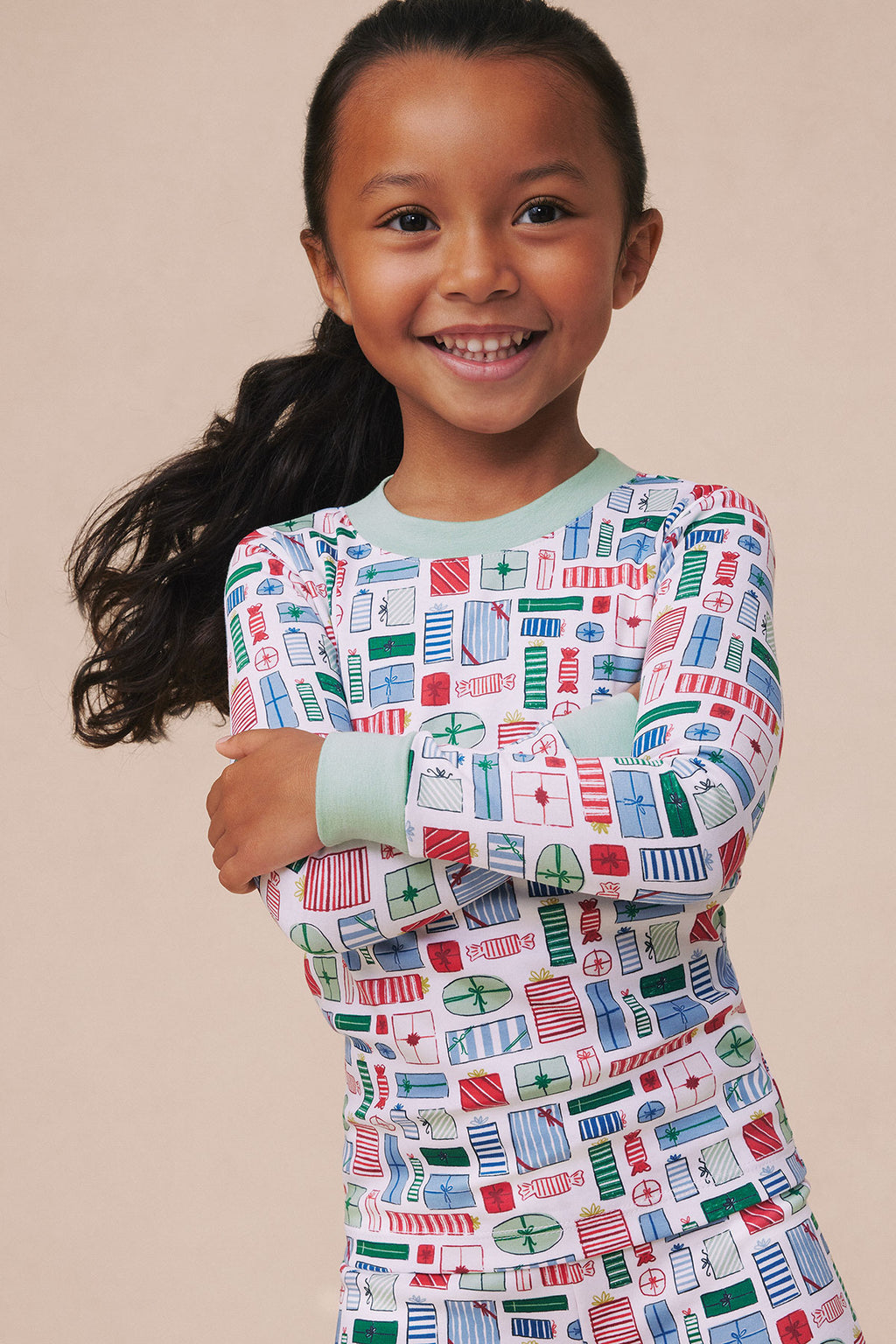 Child wearing long-sleeve pajama set with white base and colorful geometric building print in red, blue, and green.