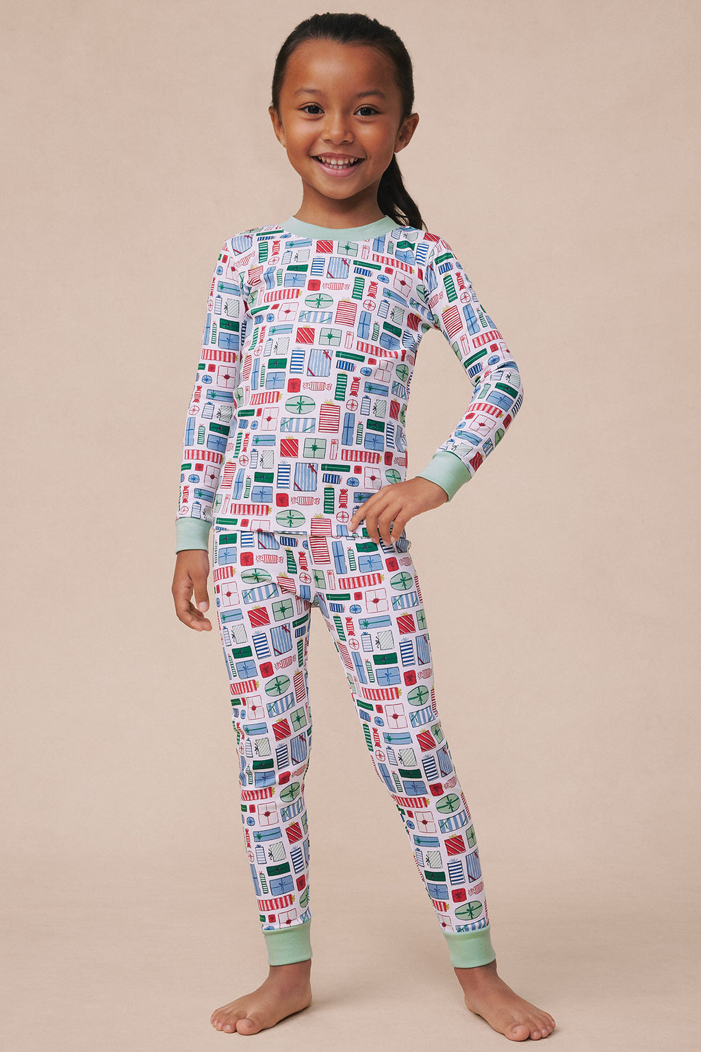 Child wearing a long-sleeve pajama set with colorful geometric print and mint green cuffs and collar.