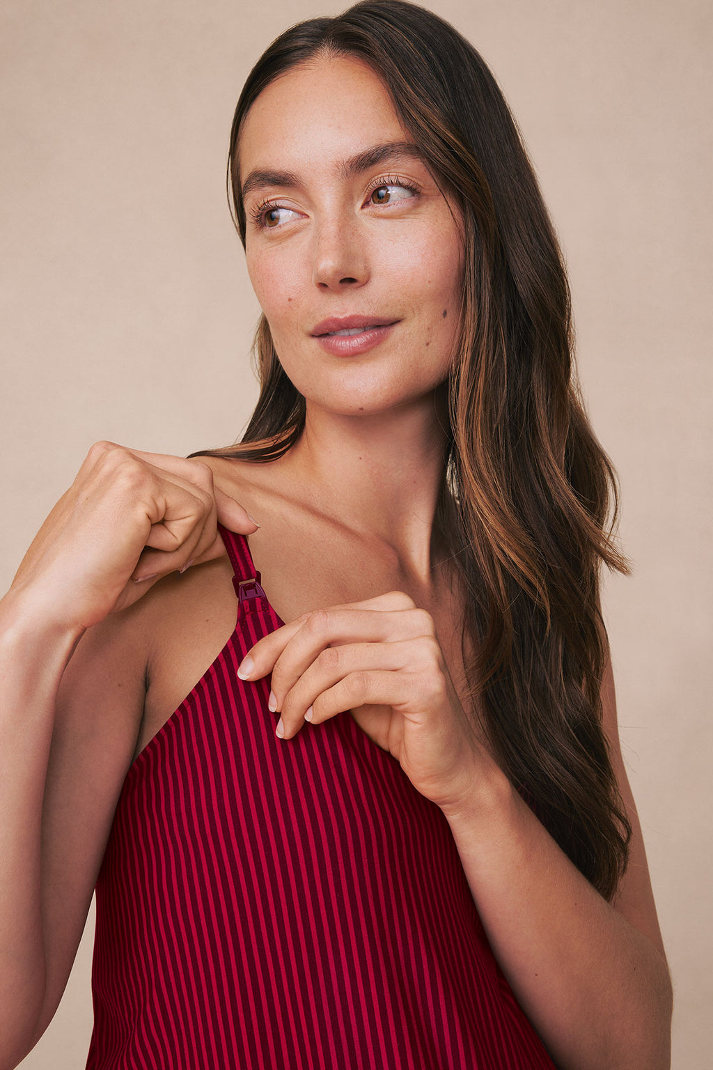 Pregnant woman wearing burgundy striped maternity tank top with thin vertical pinstripes.