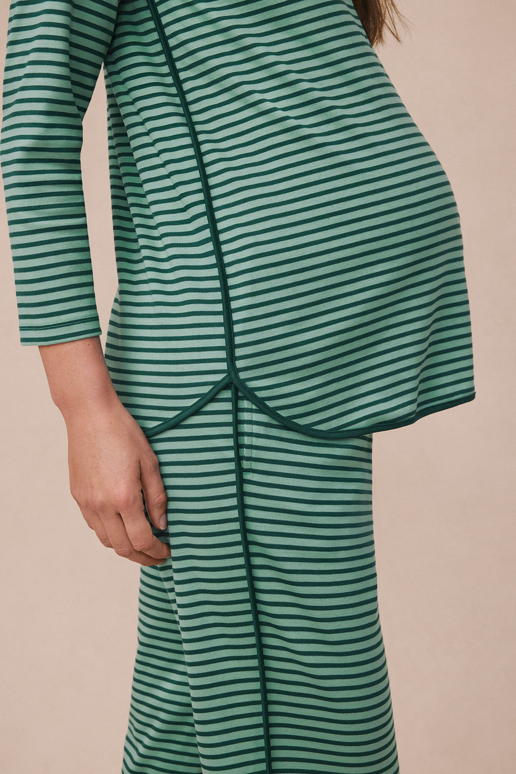 Pregnant woman wearing dark sea and light green horizontal striped long-sleeve maternity pajama top and matching pants.