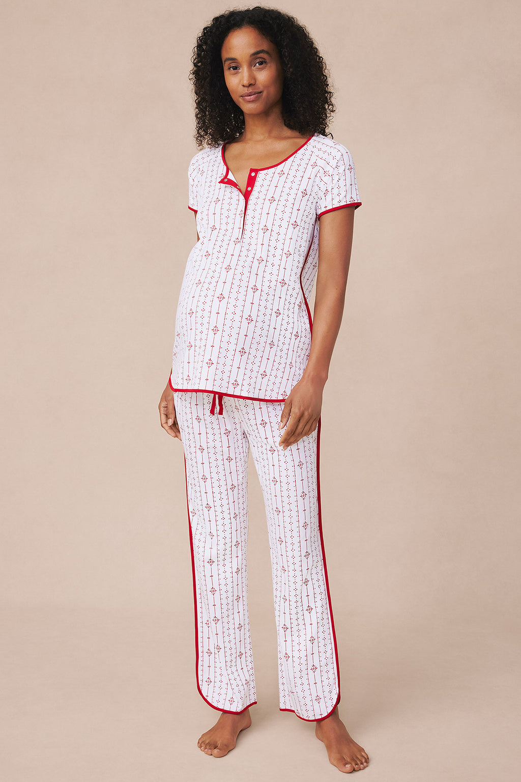 Woman wearing white short-sleeve top and long pants with red pinstripe and geometric pattern.