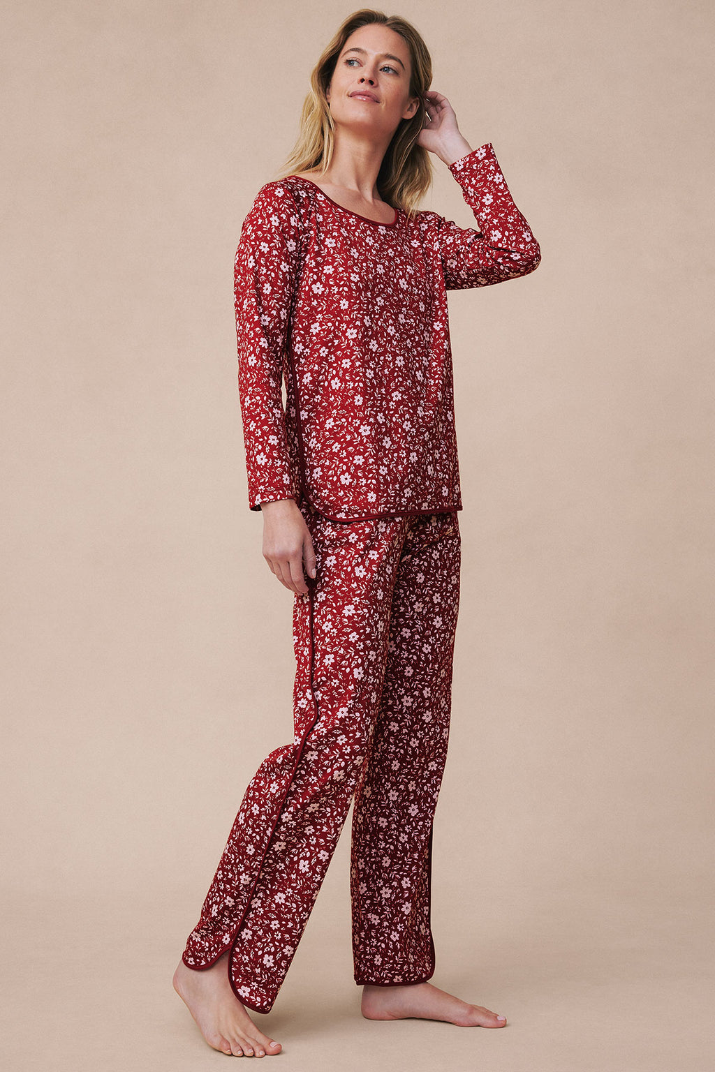 Woman wearing garnet floral long-sleeve pajama set with small white flowers throughout, shown in full-length view.