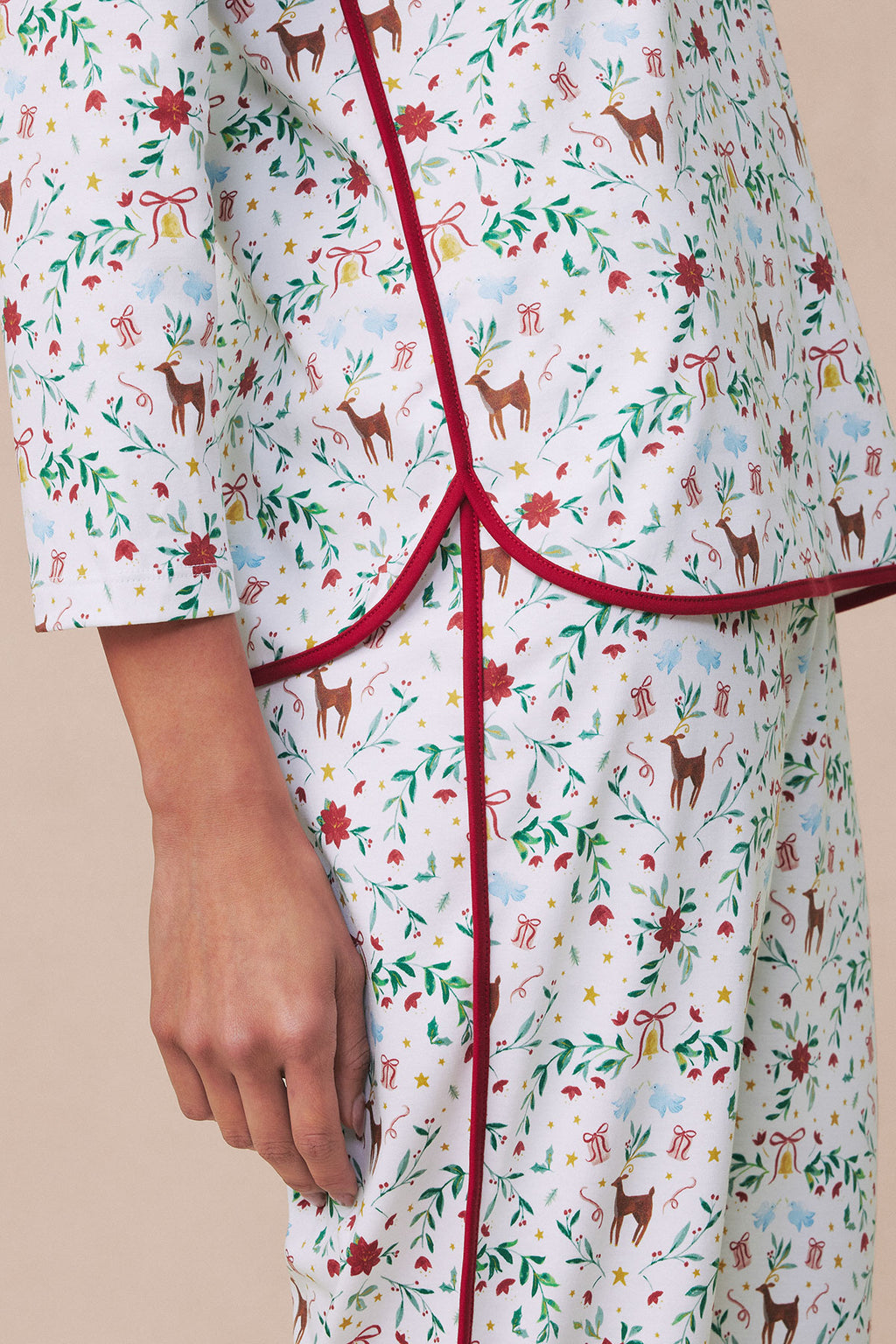 Long-sleeved pajama set in white with holiday print featuring reindeer, florals, stars, and gift bows with burgundy trim.