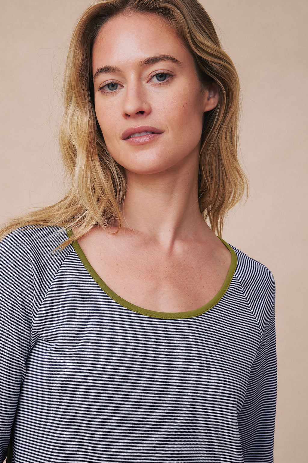 Woman wearing navy and white striped long sleeve nightgown with olive trim neckline.