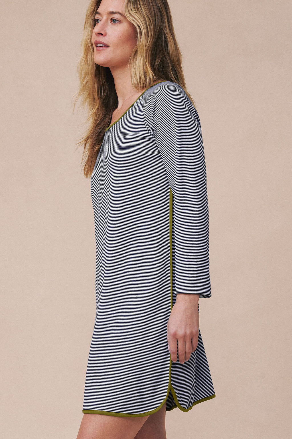 Woman wearing navy and white striped long-sleeve nightgown with green trim at hem.
