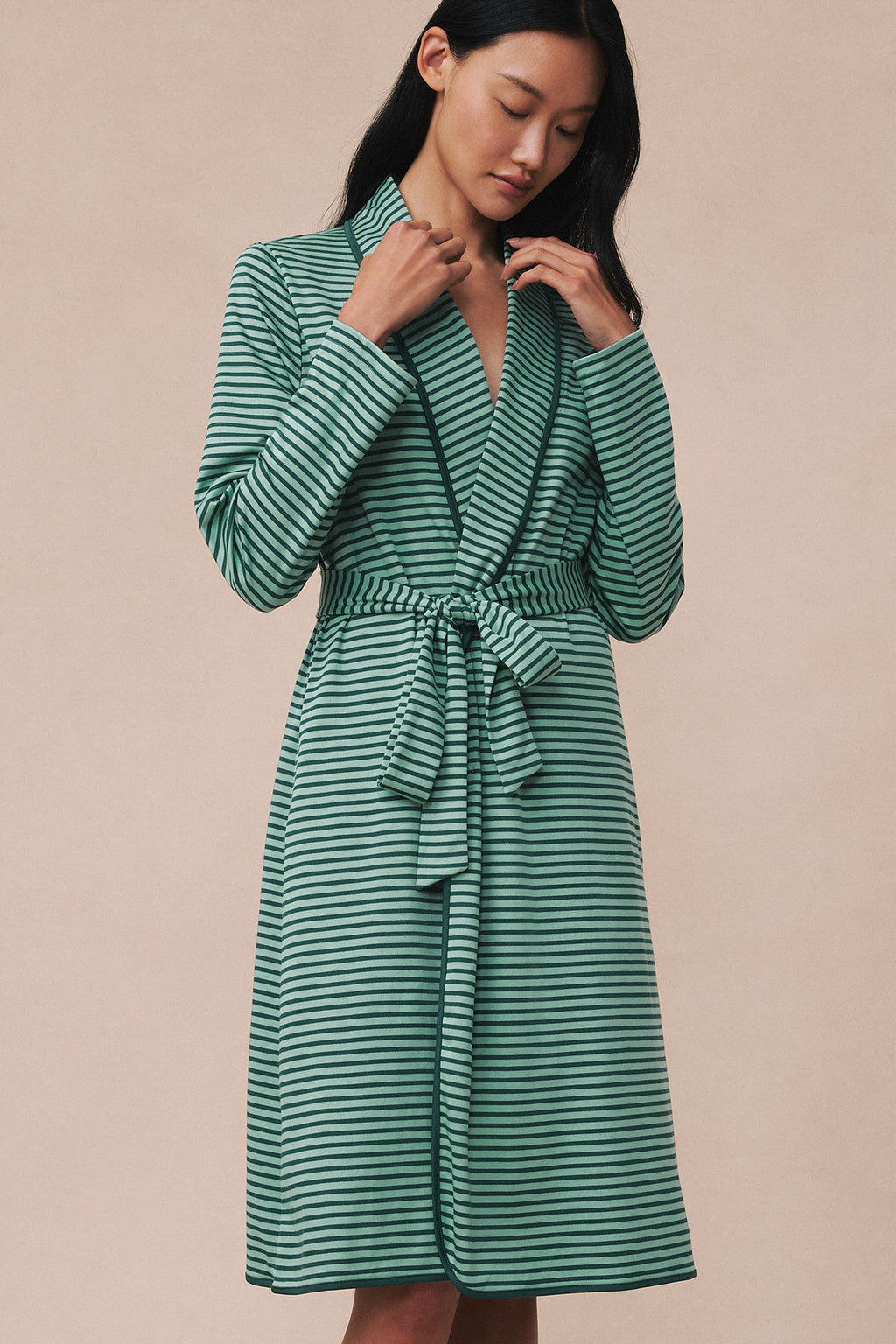 Woman wearing a dark green and light blue striped robe with a wrap front and tied waist belt.