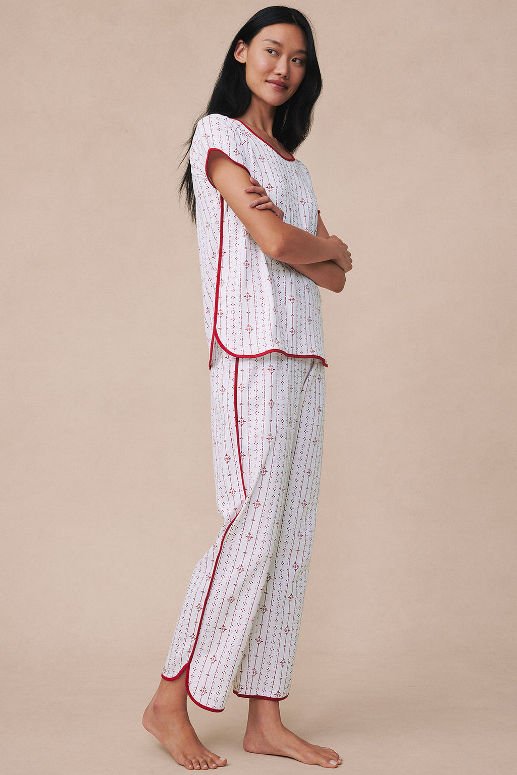 Woman wearing white short-sleeve top and long pants with red stripe pattern and red trim throughout.