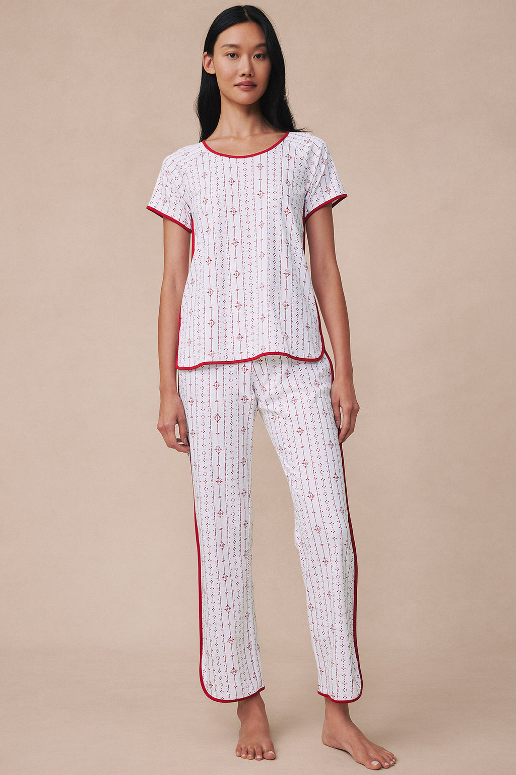Woman wearing white short-sleeve top and full-length pants with red vertical stripes and geometric pattern throughout.