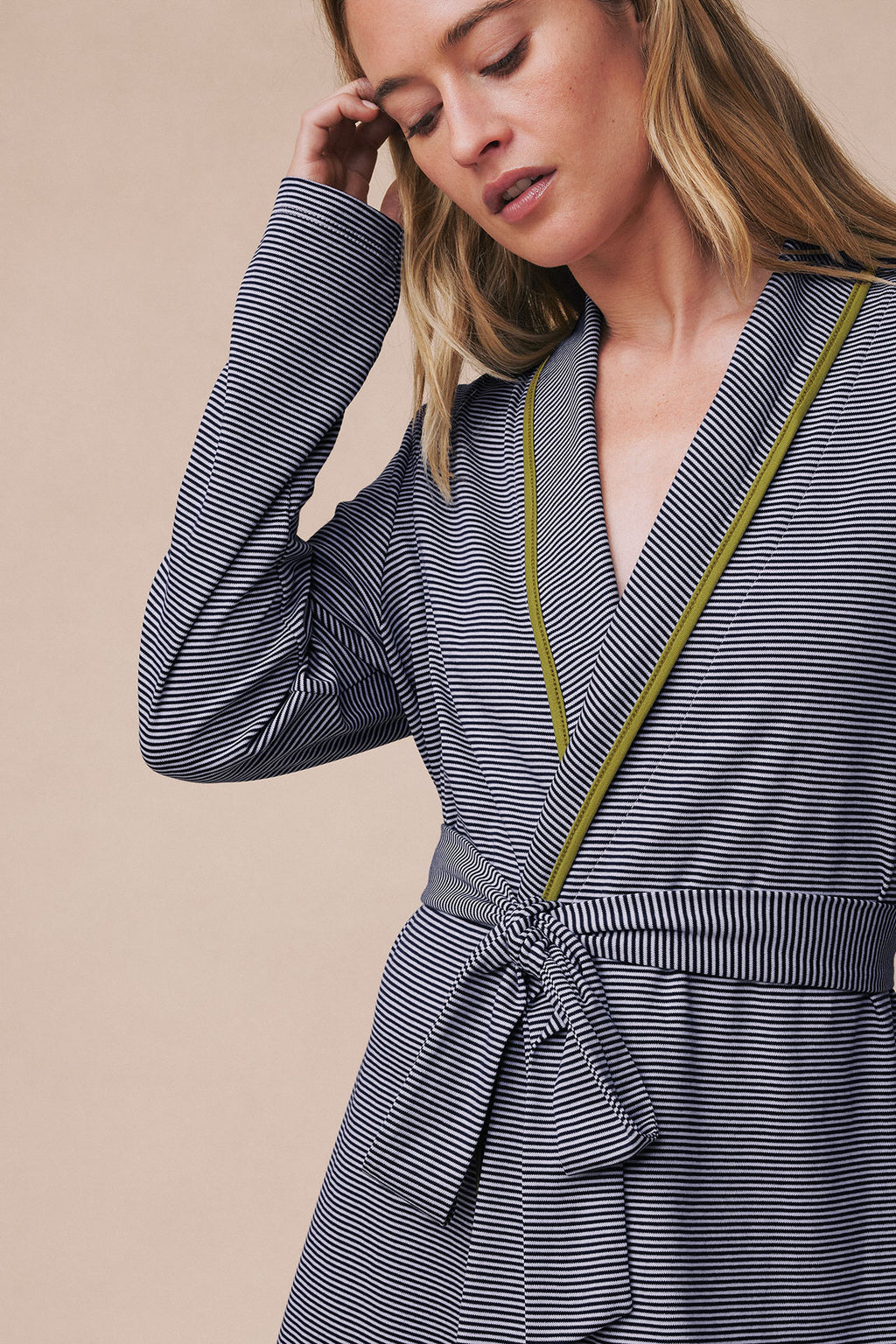 Woman wearing navy and white horizontal striped short robe with olive trim and wrap-style front closure.