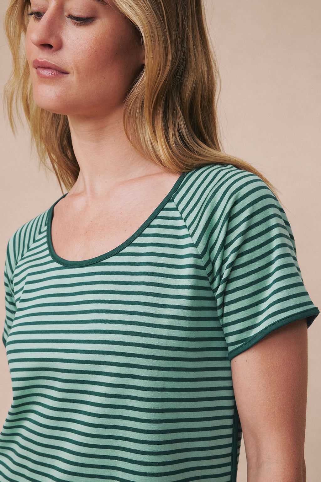 Woman wearing short-sleeved tee with dark teal and light green horizontal stripes and rounded neckline.