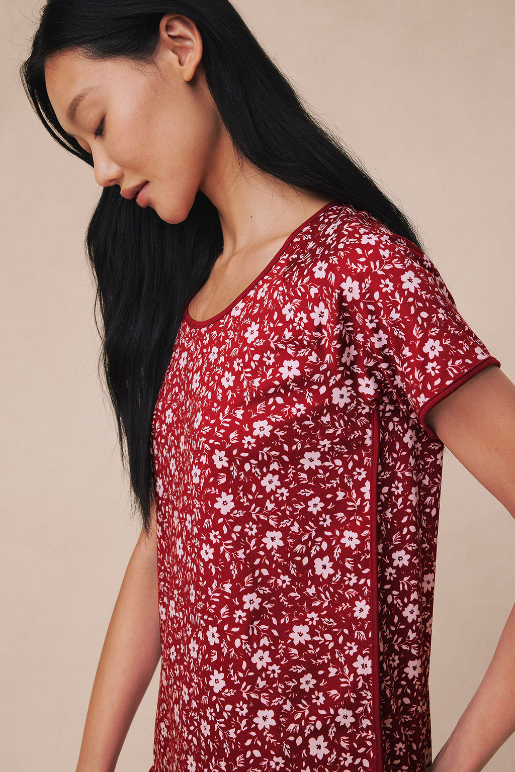 Garnet red short-sleeve top with white floral and leaf print, shown on model in profile view.
