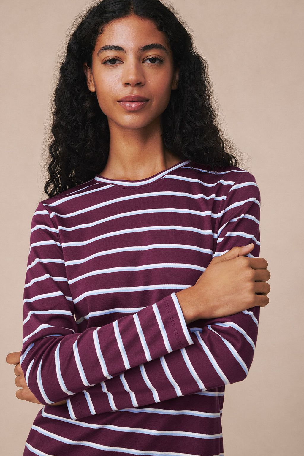 Woman wearing burgundy, white, and blue striped long-sleeve crew neck shirt.
