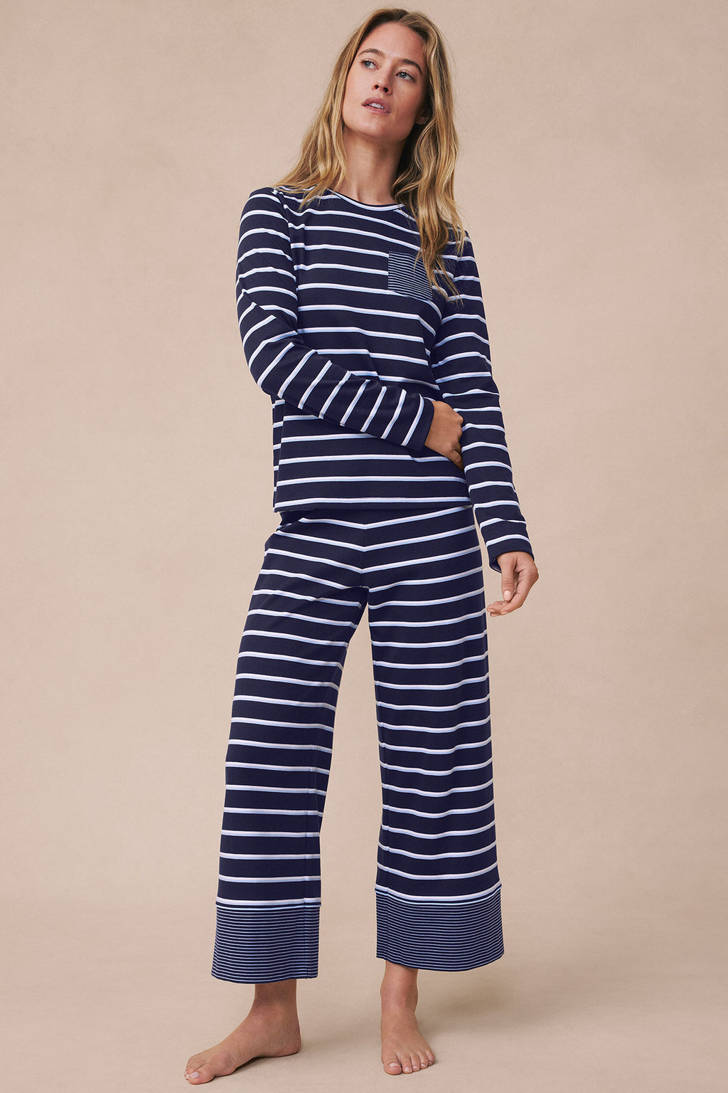 Woman wearing navy and white striped long-sleeve pajama top and wide-leg cropped pants with striped cuff detail.