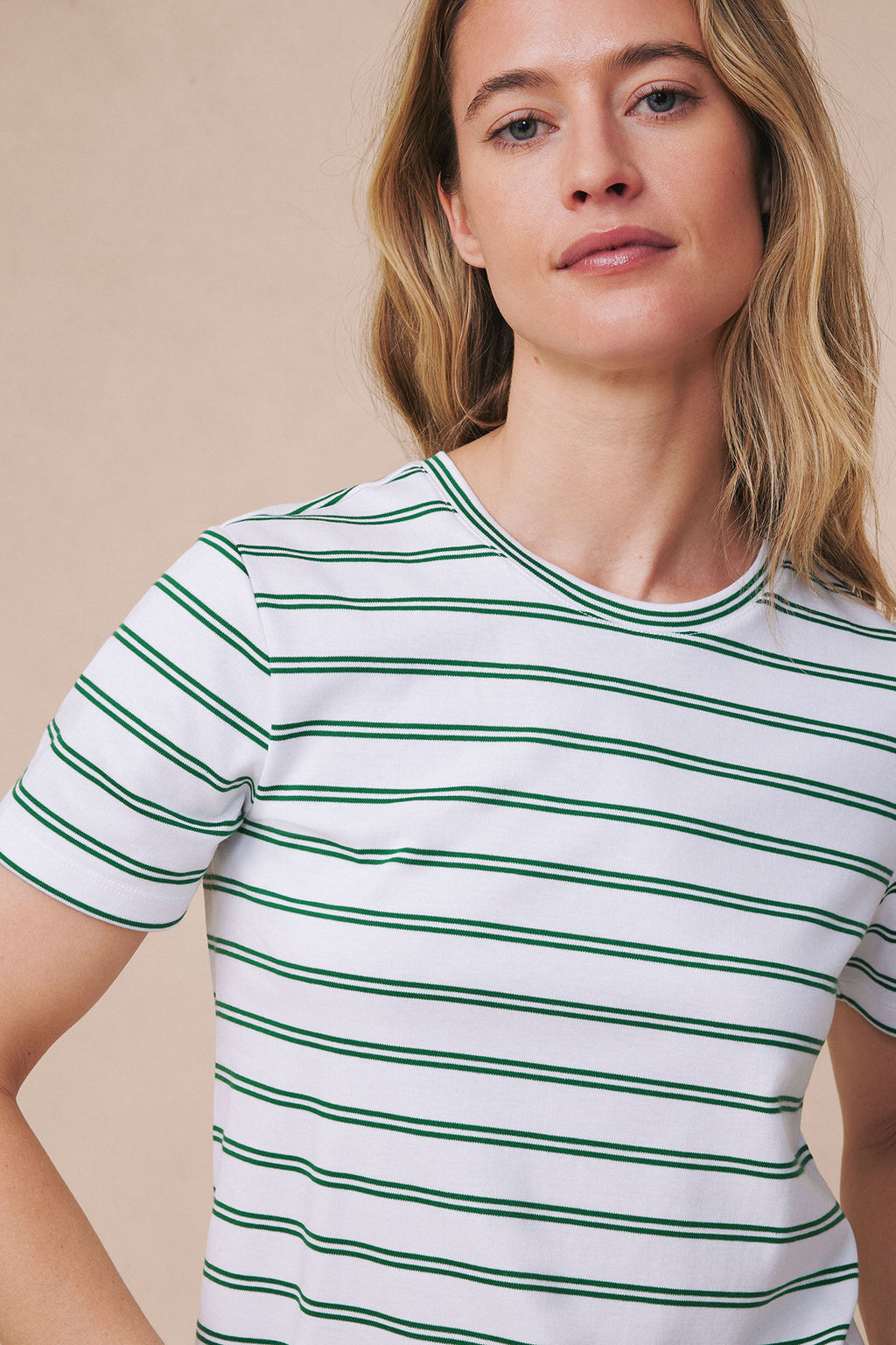 Woman wearing white short-sleeve crew neck shirt with green horizontal stripes.