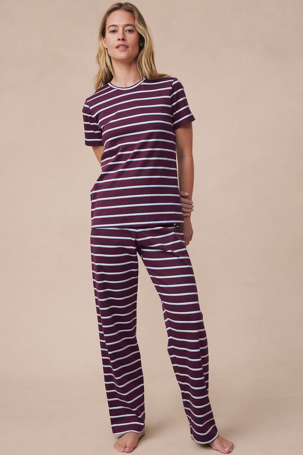 Woman wearing burgundy and white striped short-sleeve crew neck top and matching long pajama pants.