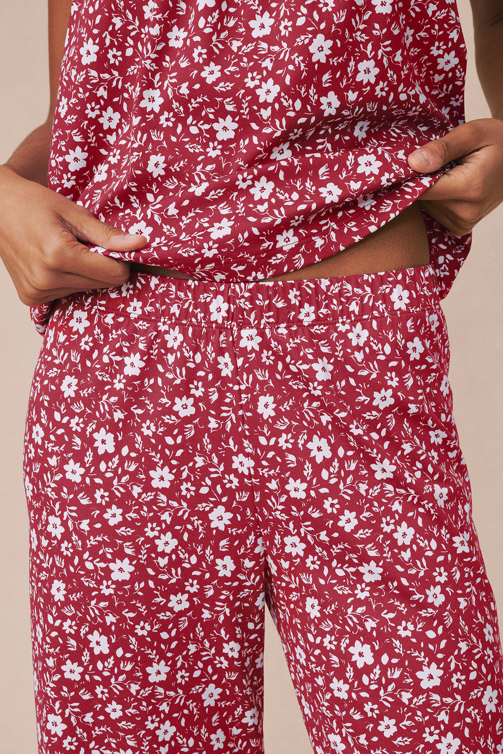 Garnet Pima pants with white floral and leaf print, featuring ruffled hem detail at ankles.