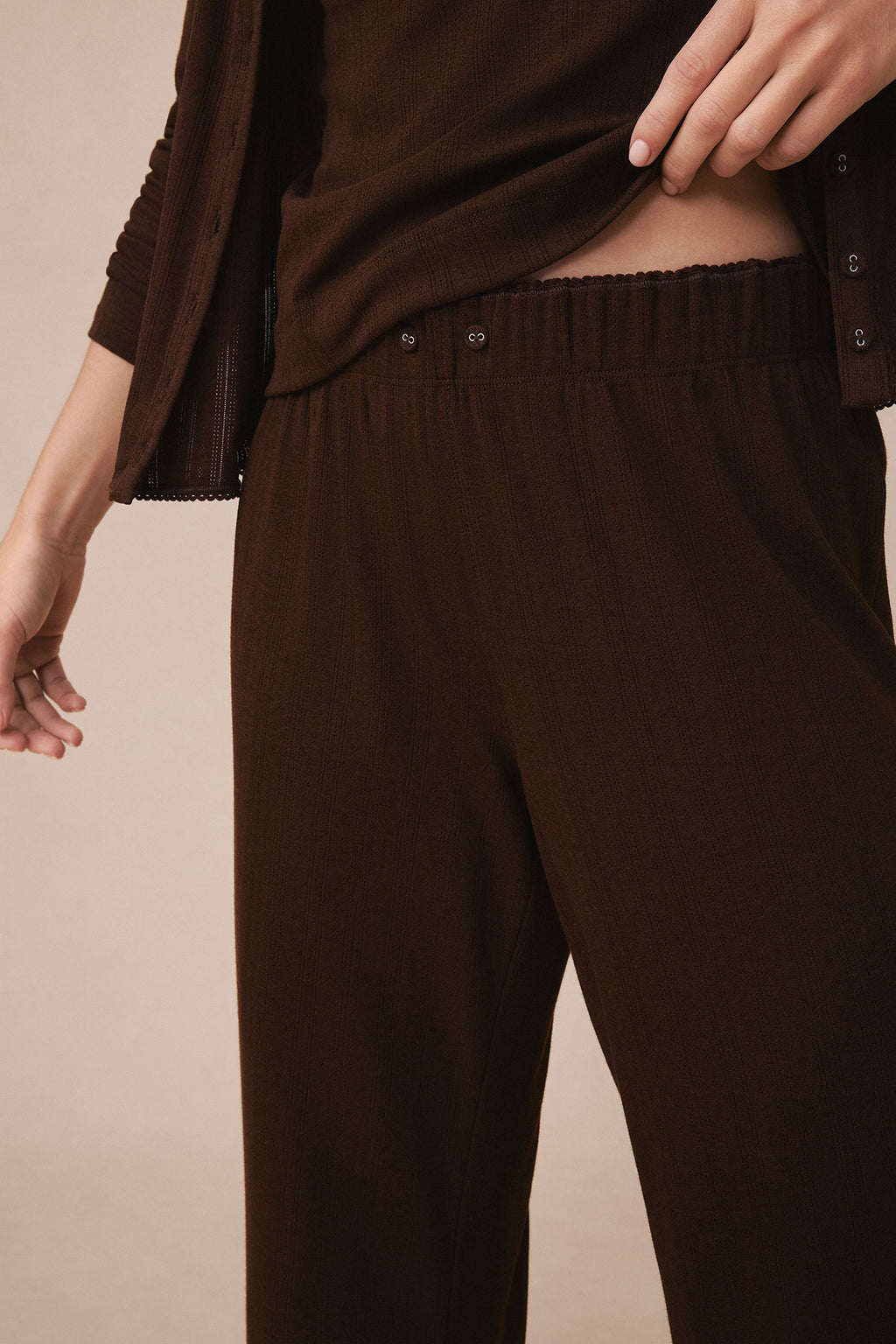 Brown pointelle cardigan and matching pants set with ribbed knit texture and button details on the cardigan.