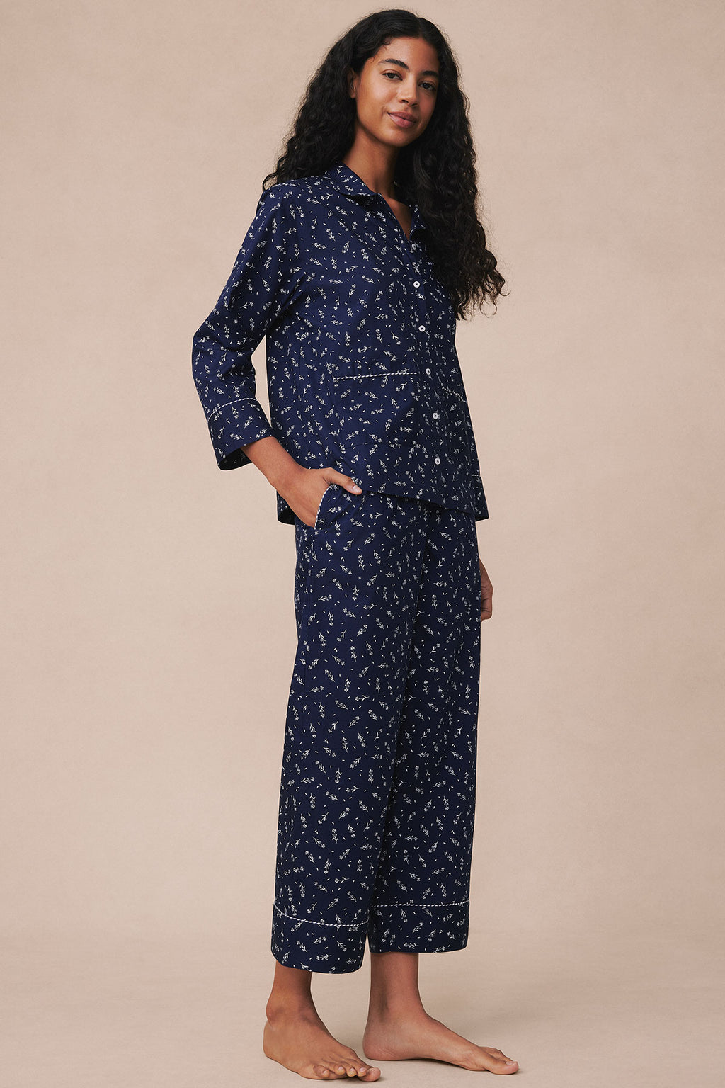 Navy long-sleeve pajama set with small floral print and contrast piping, shown on model from side.