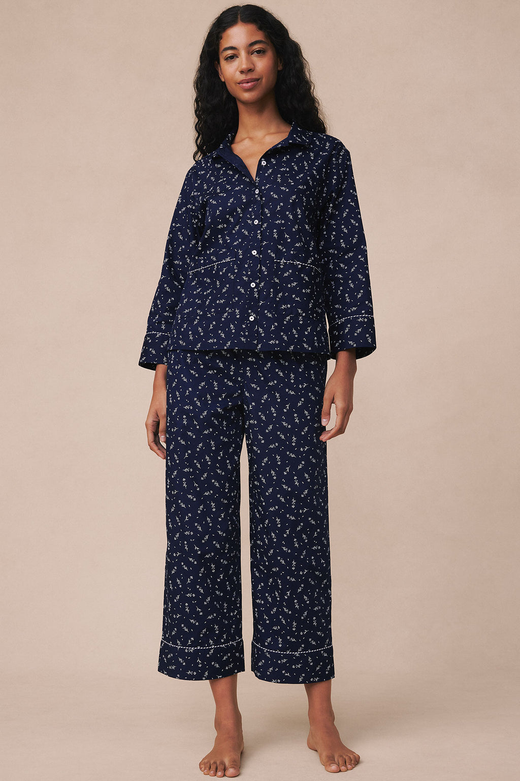 Navy long-sleeve pajama set with white floral print and piped trim details, displayed on model.