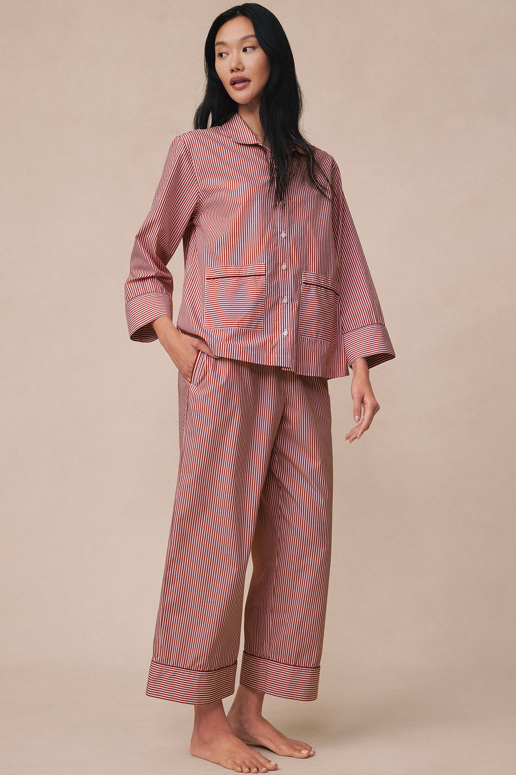 Woman wearing garnet and white striped long-sleeve pajama shirt with patch pockets and matching cropped pants with piped cuff