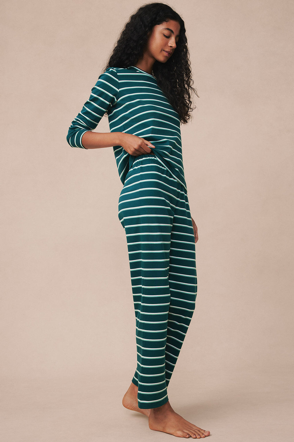 Woman wearing teal and white striped long-sleeve crew neck top and matching full-length pants.
