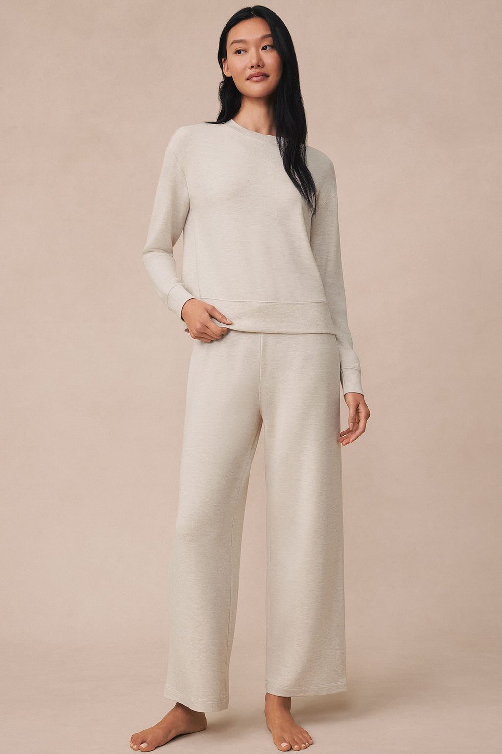Woman wearing cream heather long-sleeve crewneck sweatshirt and matching wide-leg pants.