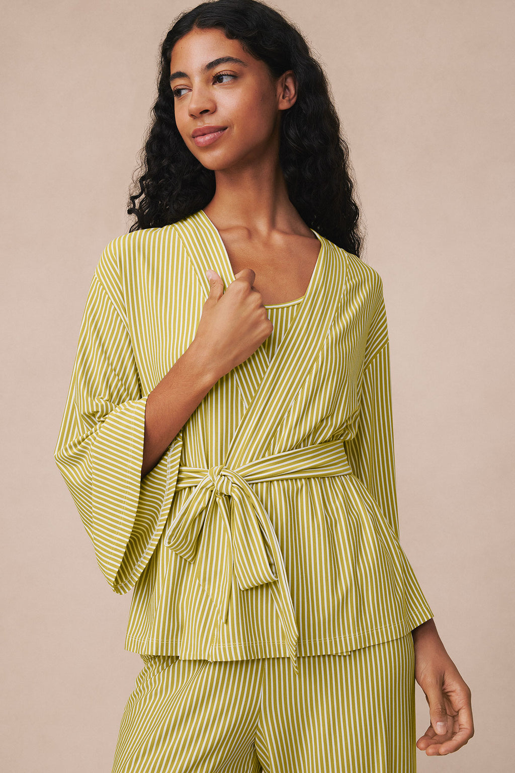 Woman wearing yellow and white vertical striped kimono jacket and matching pants with tie waist.