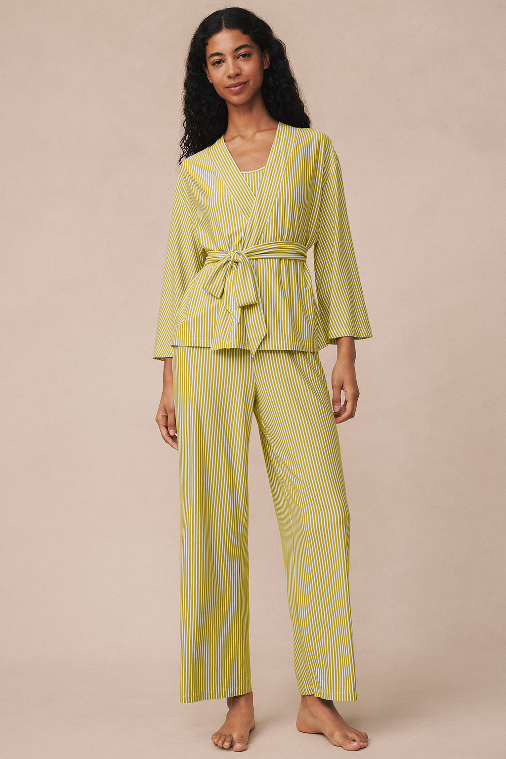 Woman wearing yellow and white vertical striped kimono top with tie belt and matching straight-leg pants.