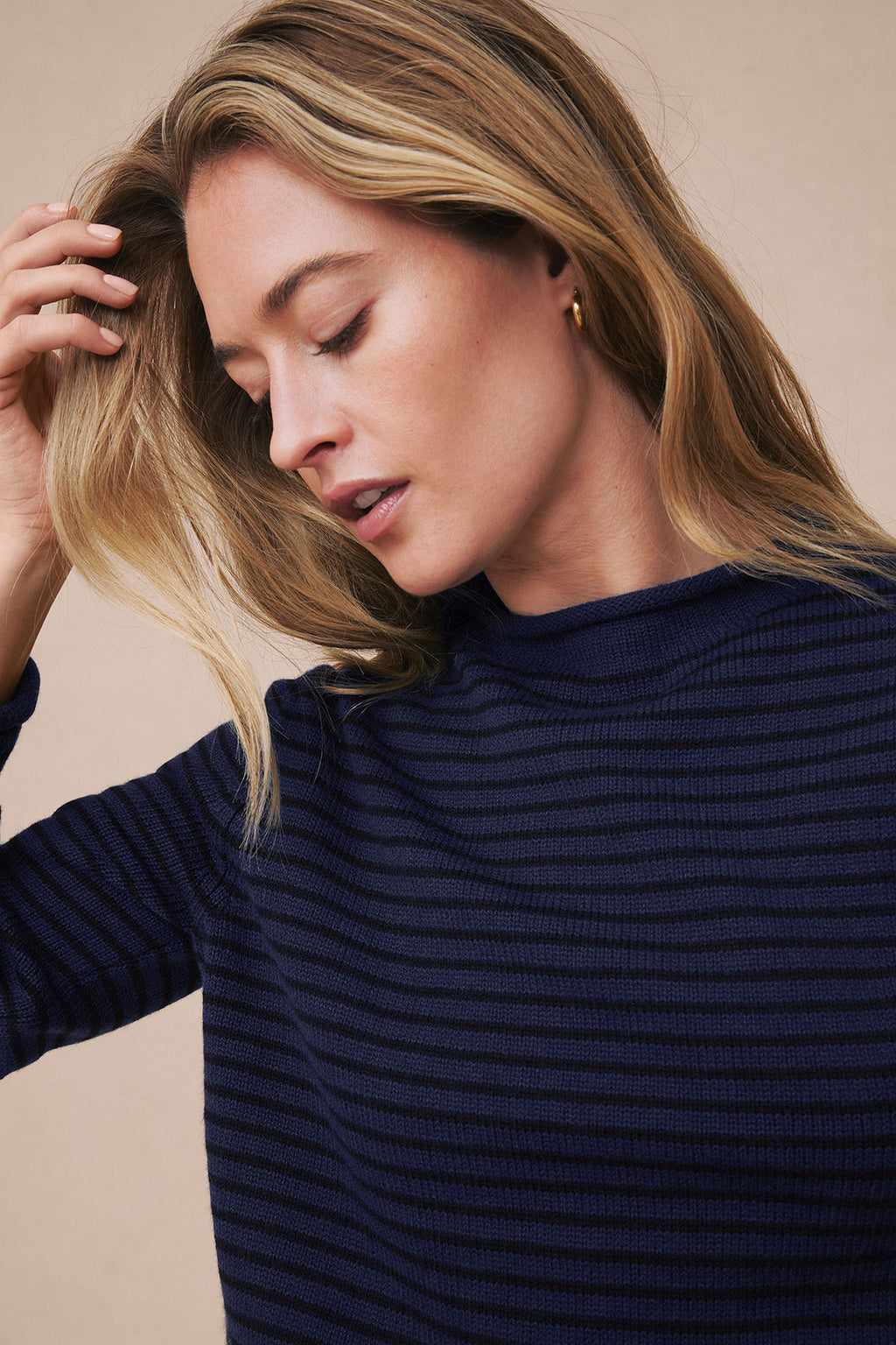 Navy and charcoal striped funnel neck sweater with long sleeves worn by model against neutral background.