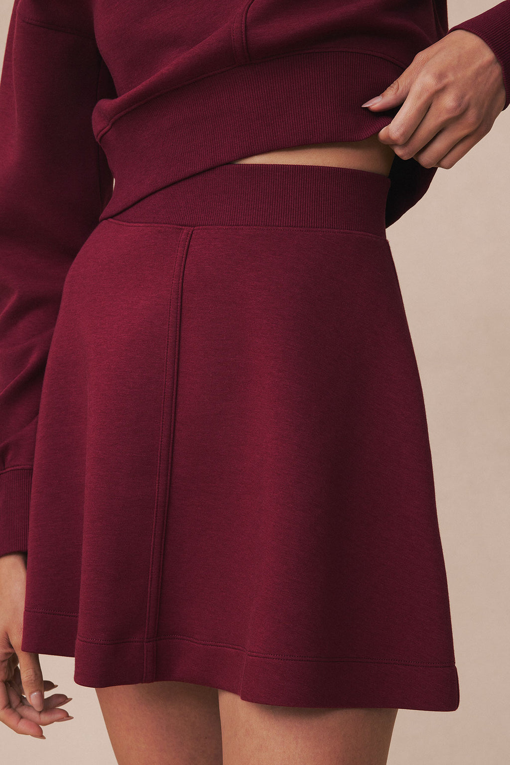 Burgundy ribbed crop top and A-line mini skirt set with cutout detail at midriff.