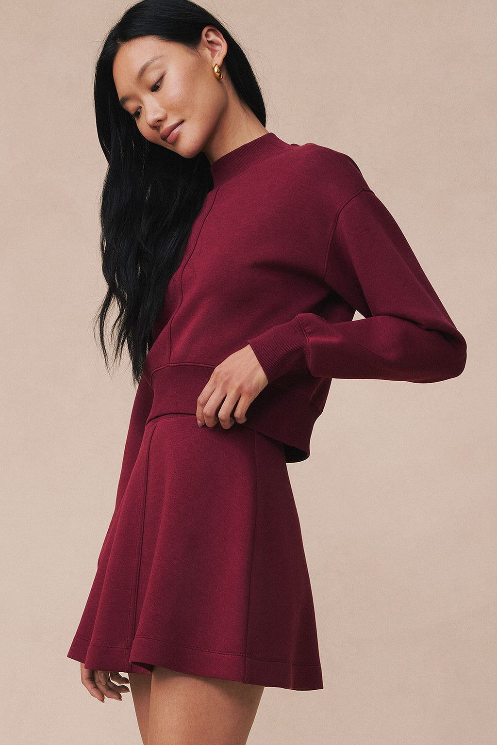 Burgundy long-sleeve top and matching mini skirt set displayed on model against neutral background.
