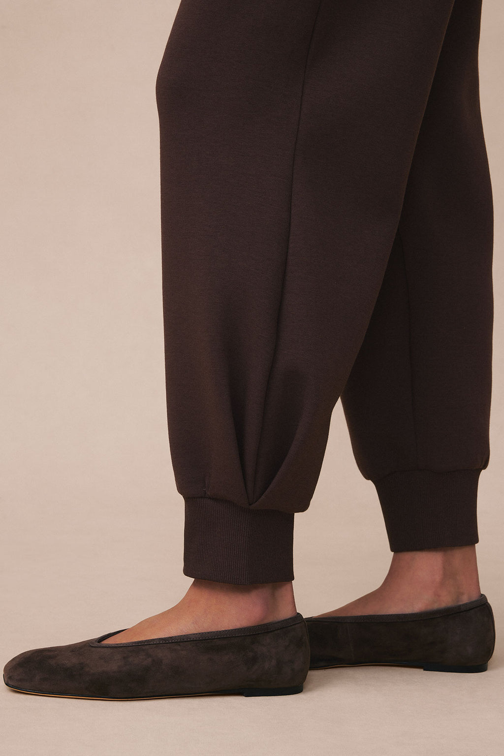 Dark brown jogger pants with ribbed cuffs and ankles worn with black suede loafers.