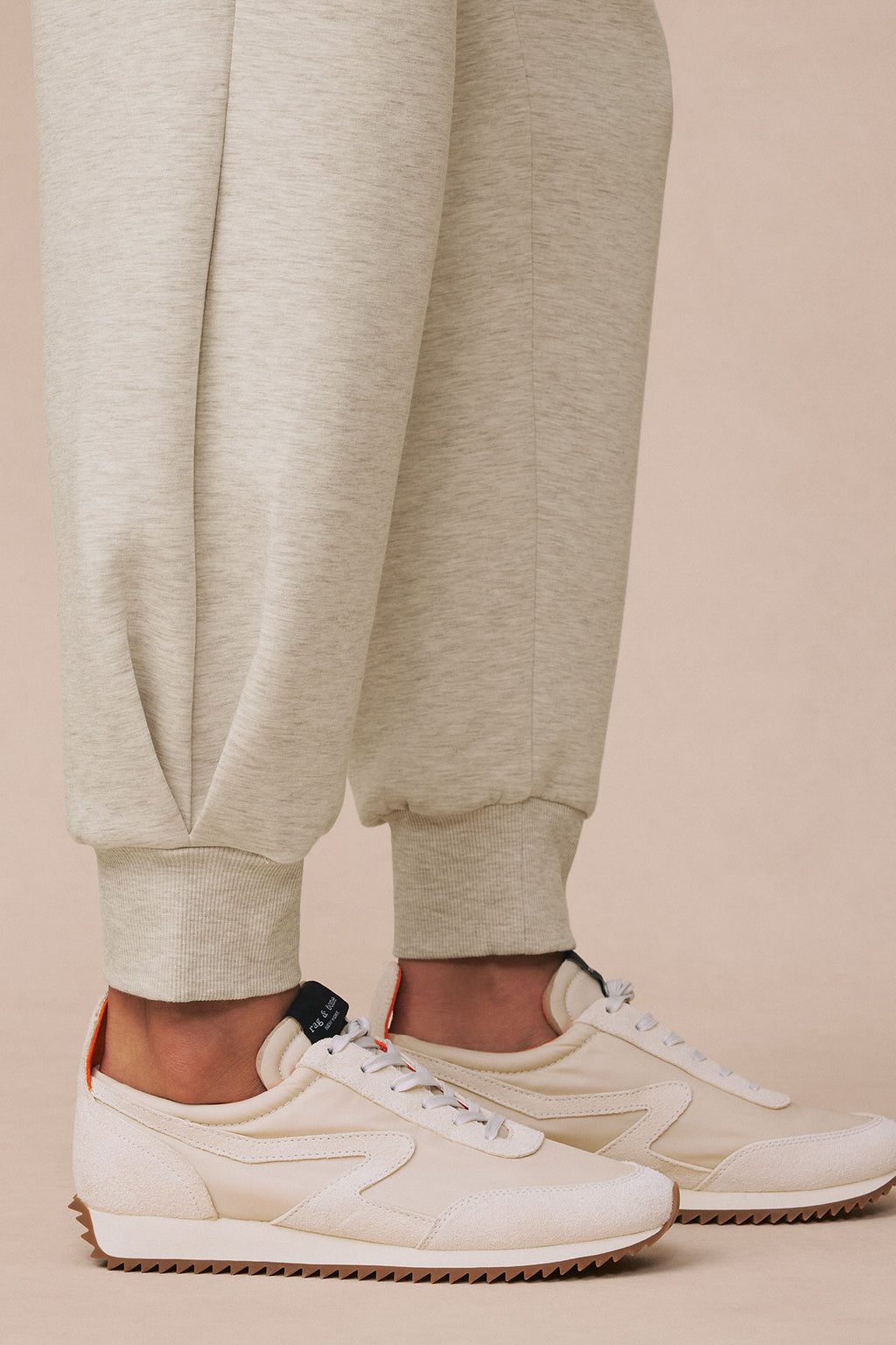 Oat heather jogger pants with ribbed cuffs paired with cream lace-up sneakers.