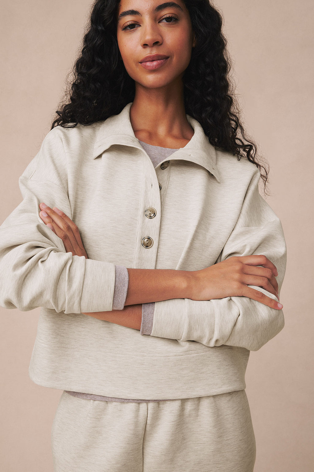 Woman wearing oat heather pullover with collar and buttons over gray shirt, paired with matching jogger pants.