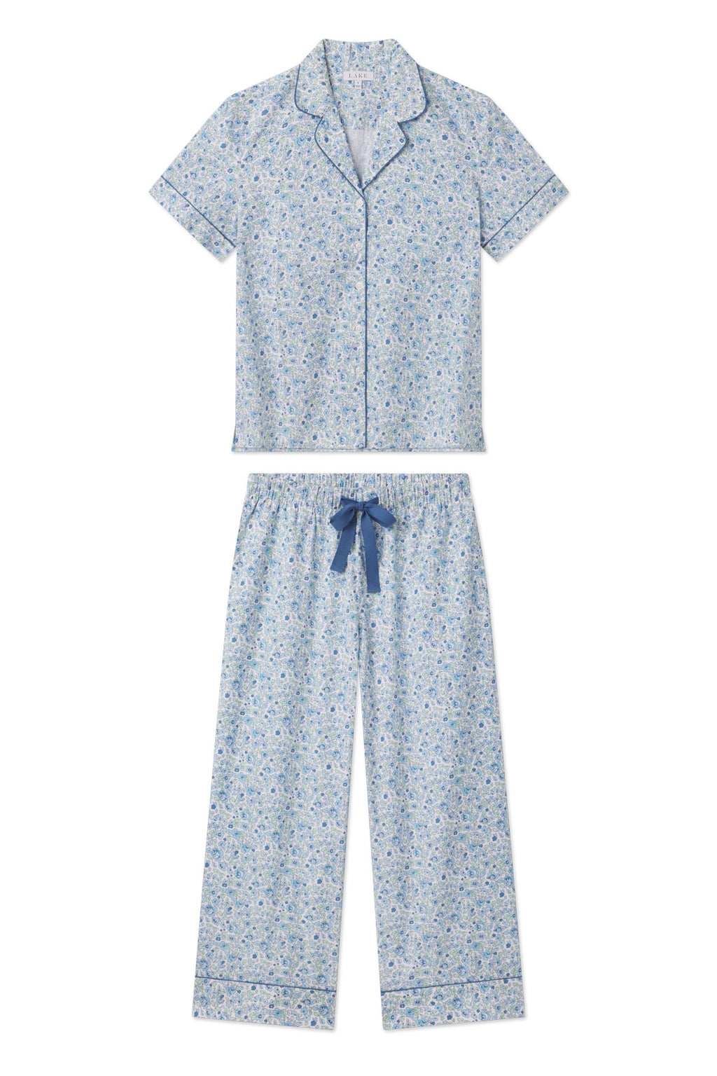 The Poplin Chloe Pajama Set in Morning Blue Elizabeth Floral is made from light blue 100% cotton poplin, featuring short sleeves, blue piping, a button-up top, and cropped pants with a blue drawstring waist.