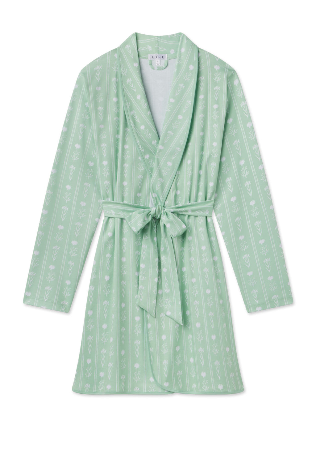 The Pima Short Robe in Parisian Green Watercolor Stems is a light green, knee-length 100% Pima cotton robe with long sleeves, a matching belt, shawl collar, and subtle white floral pattern.