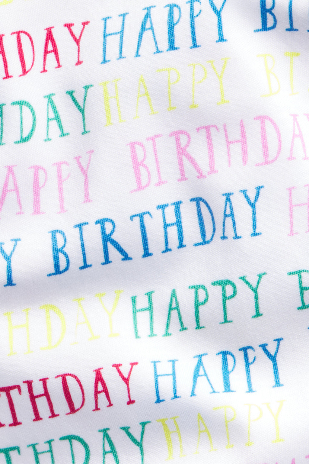 The Kids Shorts Set in Happy Birthday is a white 100% Pima cotton set with an elastic waistband, featuring HAPPY BIRTHDAY in green, yellow, blue, pink, and blue uppercase letters for a festive look.