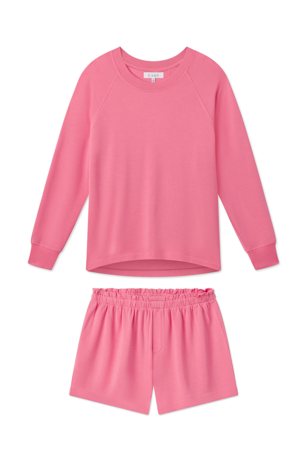 The Relax Shorts Set in Sunkissed Coral, featuring a long-sleeve crewneck top and elastic-waist shorts, is shown laid flat on a white background.