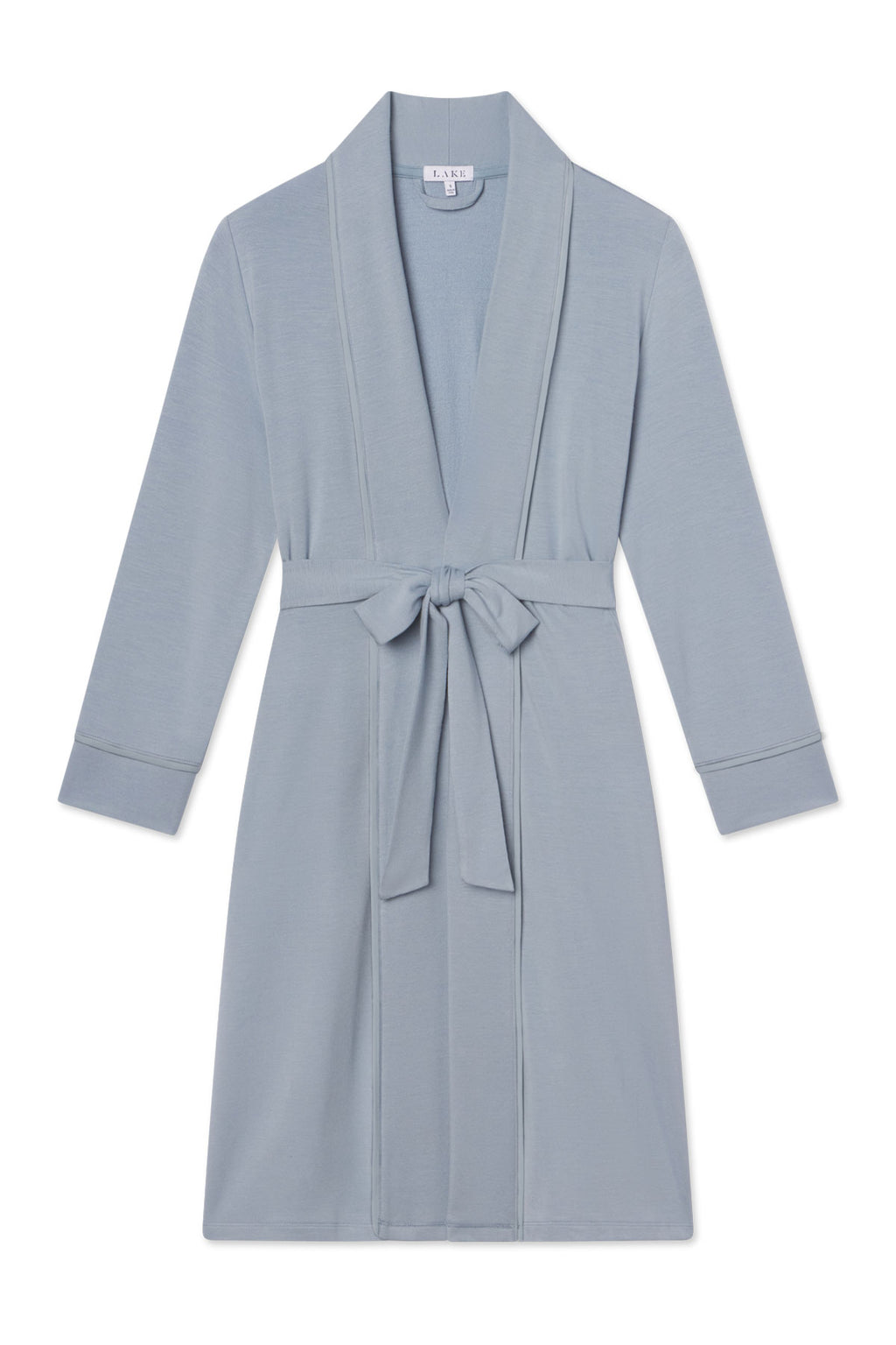 The Relax Robe in Dusty Blue is a knee-length modal robe with long sleeves, a shawl collar, and a matching fabric belt tied at the waist. It’s shown laid flat on a white background.