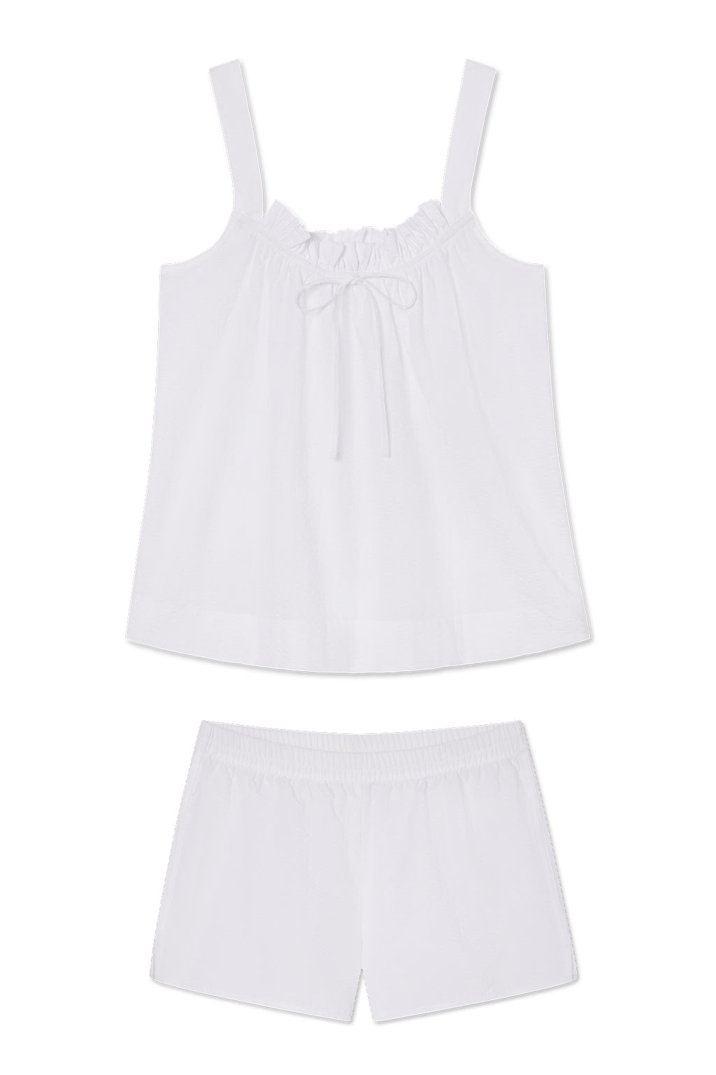 The Alice Shorts Set in White Seersucker features a sleeveless, loose-fitting top with a ruffled neckline and front bow, paired with matching elastic-waist shorts.