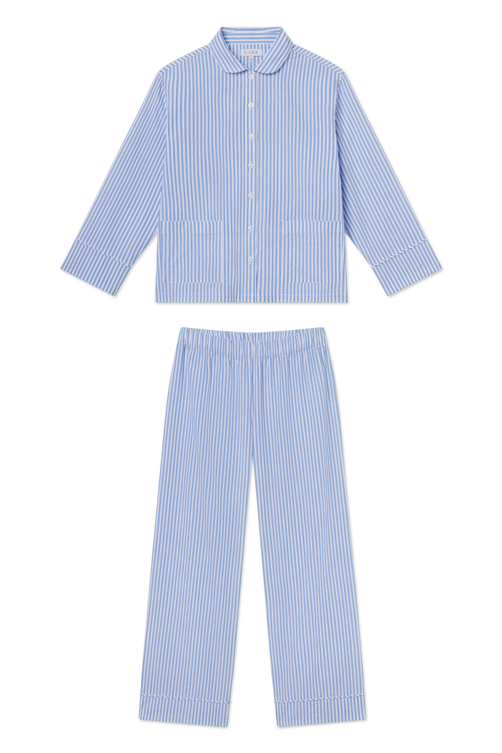 The Georgie Pocket Pants Set in Blue Seersucker is a two-piece pajama set with classic blue and white stripes, featuring a long-sleeve button-up top with pockets and matching elastic-waist pants.