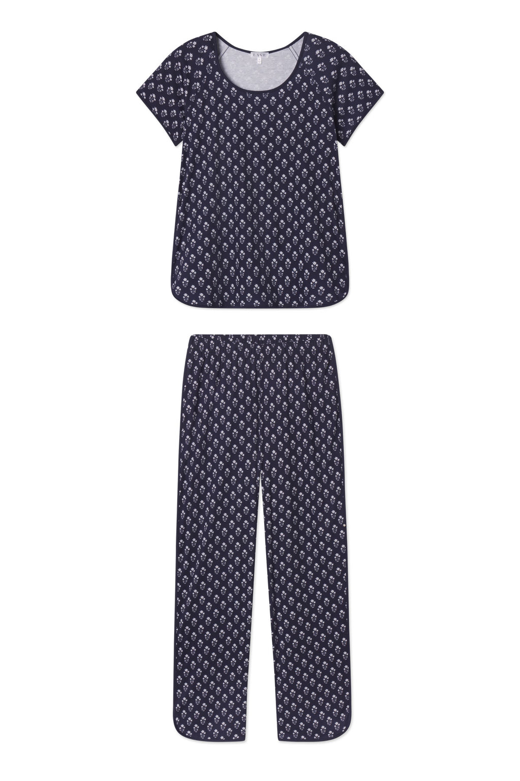 The Pima Short-Long Set in English Navy Posy features a soft Pima cotton pajama set with a short-sleeve top and long pants, both in dark blue with a small white geometric pattern and an elastic waistband.