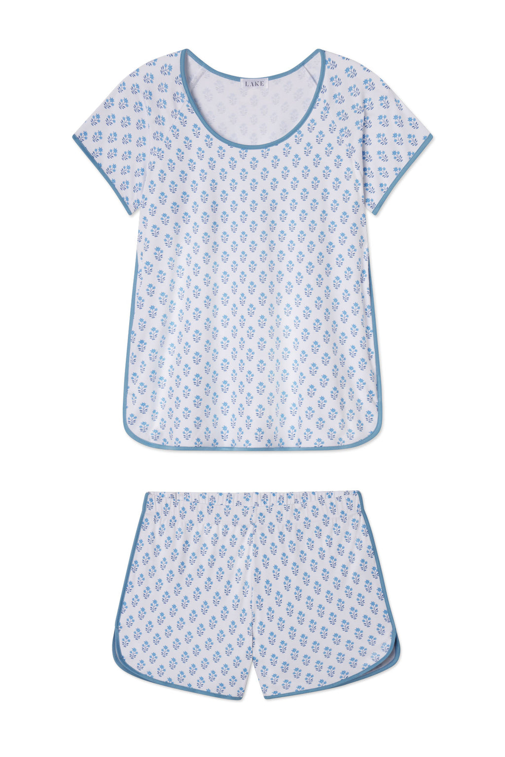 The Pima Shorts Set in Serene Blue Posy features soft Pima cotton, a short-sleeve scoop-neck top, and shorts with blue trim in a Serene Blue Inverse Posy print on a white background.