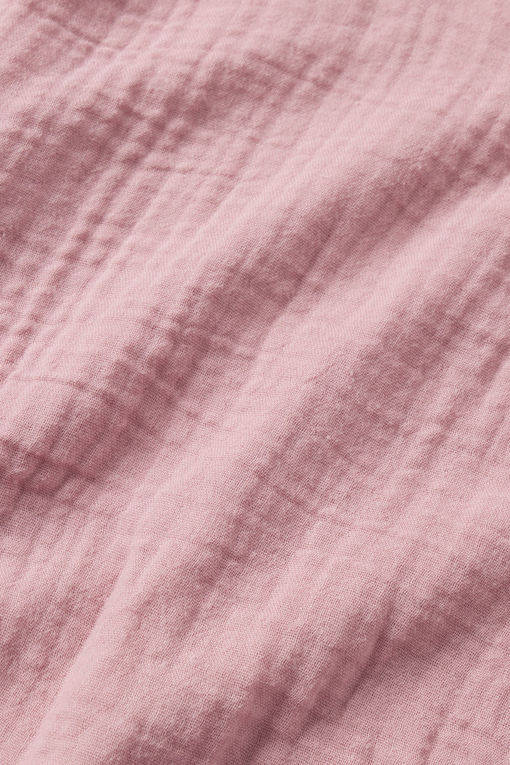 Close-up of pink crumpled fabric with soft folds and gentle shadows, inspired by the relaxed fit and subtle texture of the Nantucket Shorts Set in Carnation.