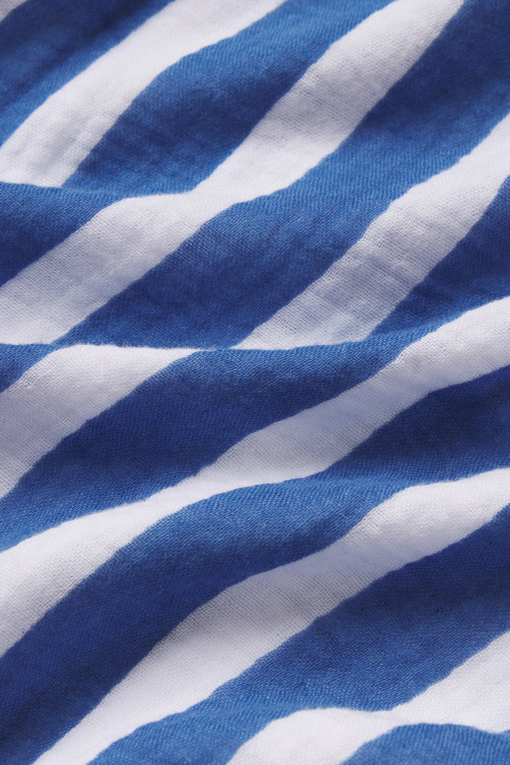 Close-up of blue and white Seaport Sail Stripe on textured cotton gauze fabric from the Nantucket Pants Set, with visible folds and shadows adding depth and softness.