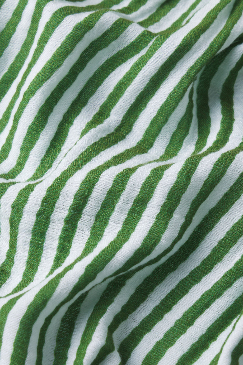 Close-up of gauze fabric with green and white stripes in the Hamptons Pants Set in Palm Awning Stripe, featuring an undulating, textured pattern—ideal for hot sleepers or anyone seeking comfort.