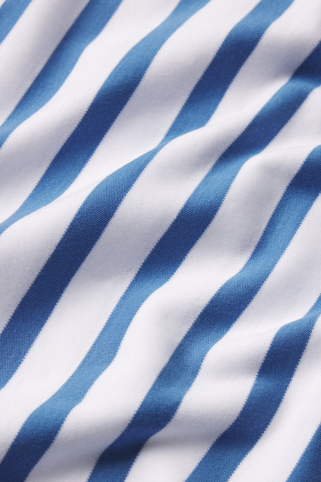 Close-up of the Pima Long Sleeve Bundle in Seaport Stripe, featuring soft Pima cotton fabric with diagonal blue and white stripes, gentle folds, and a smooth texture that creates a flowing striped pattern.