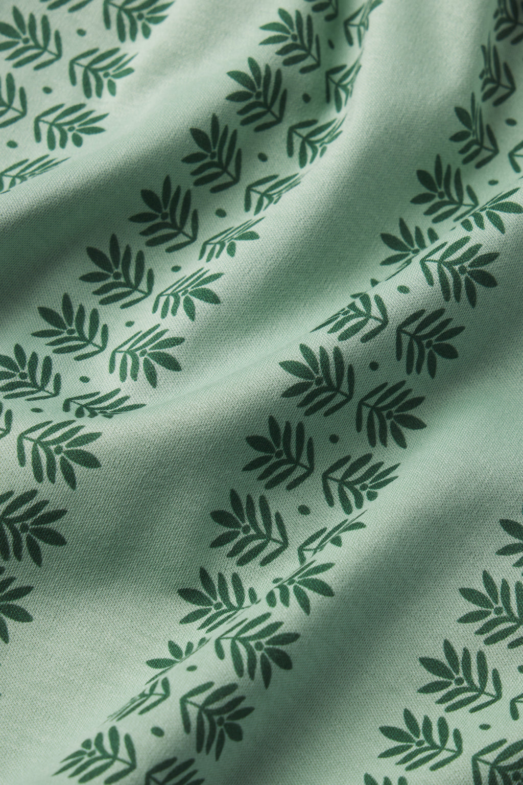 Close-up of the Pima Ruffle Nightgown in Granite Green Trellis, showcasing a dark green leaf and branch pattern in horizontal rows on soft, slightly wrinkled Pima cotton for a premium look and feel.