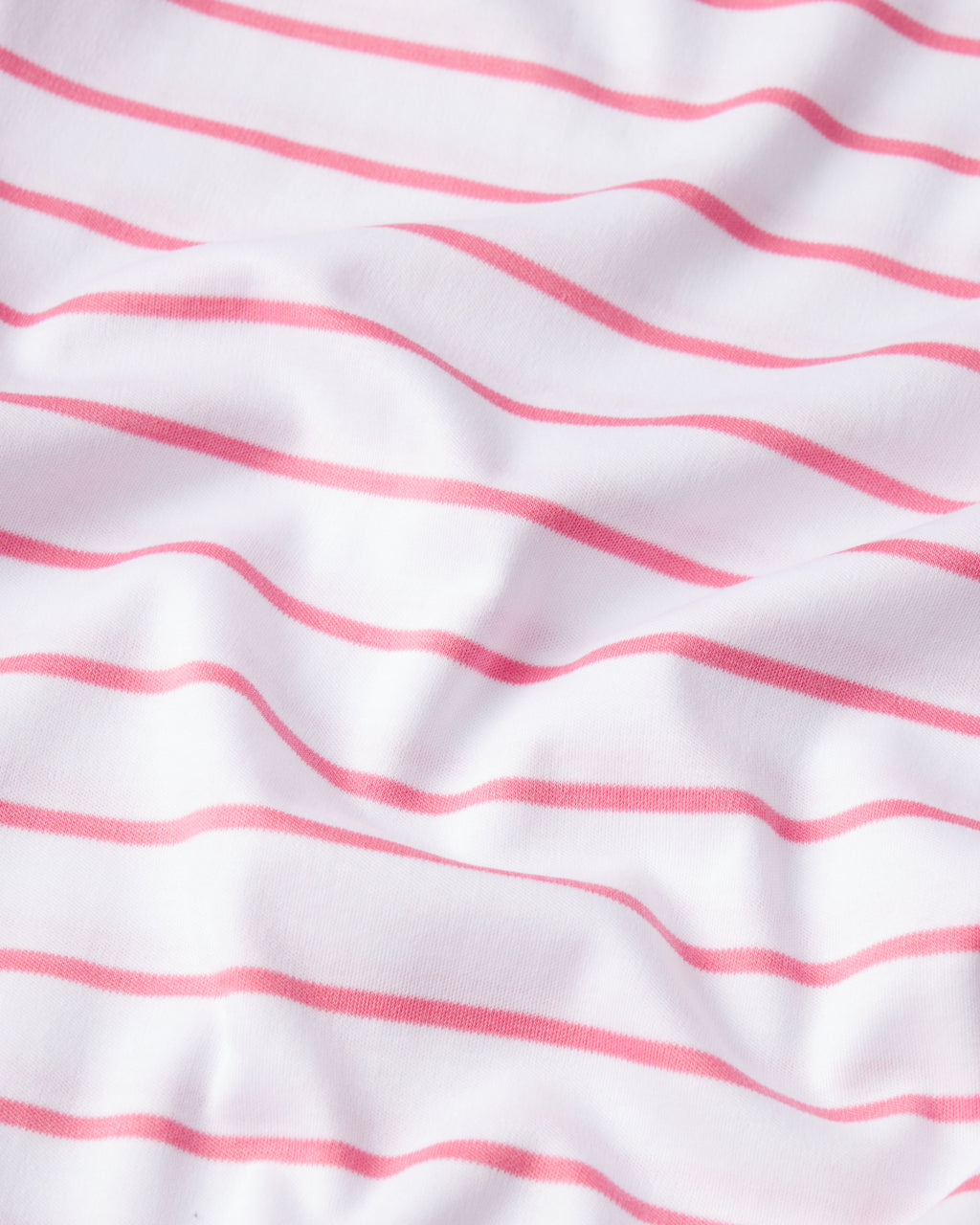 A close-up of the Pima Shorts Set in Sunkissed Coral Club Stripe, showing white Pima cotton fabric with horizontal coral stripes and soft, gentle folds.